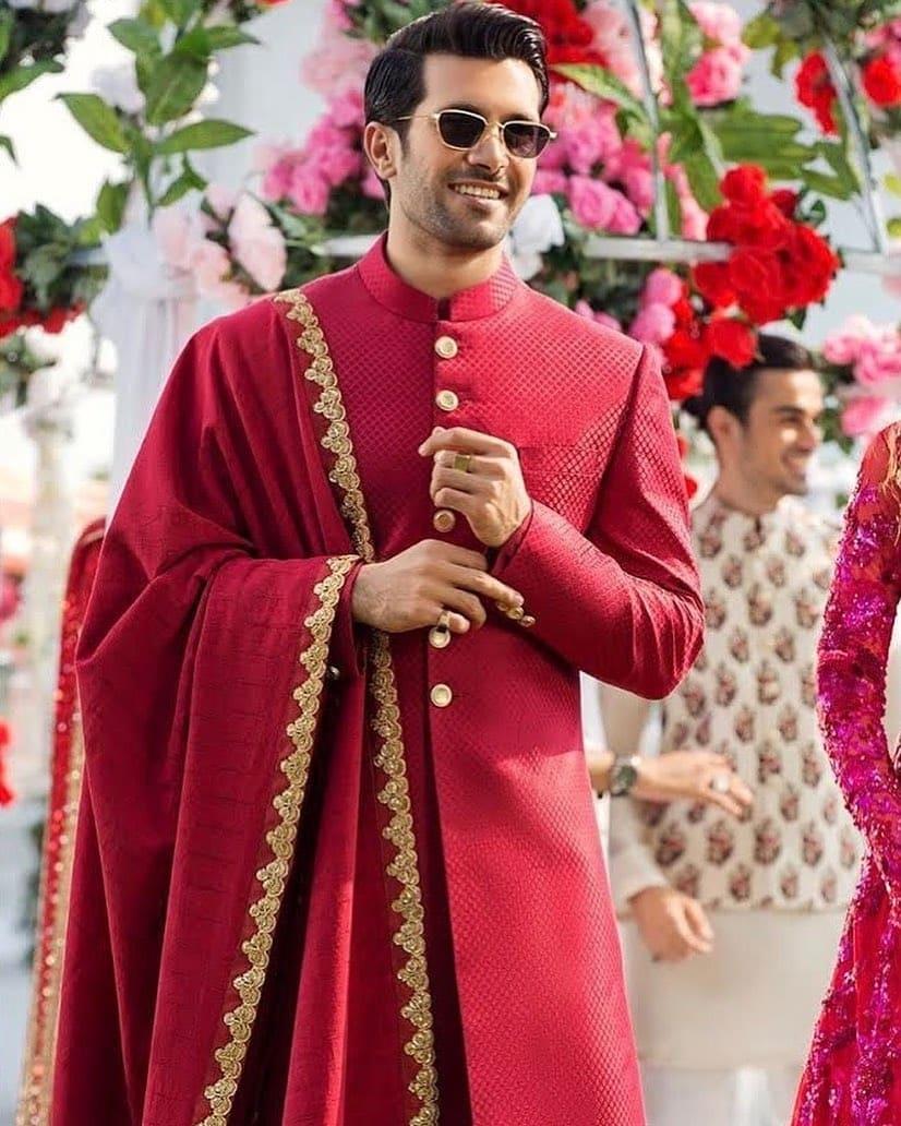 Indian groom dressed in white Sherwani and red hat with stunning bride in red  lehenga stand and hold each hands walking outside Stock Illustration |  Adobe Stock