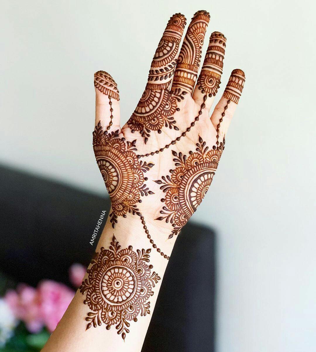 A woman is being decorated with Henna tattoo on her hand one day ahead of  the Hindu holy month of ...