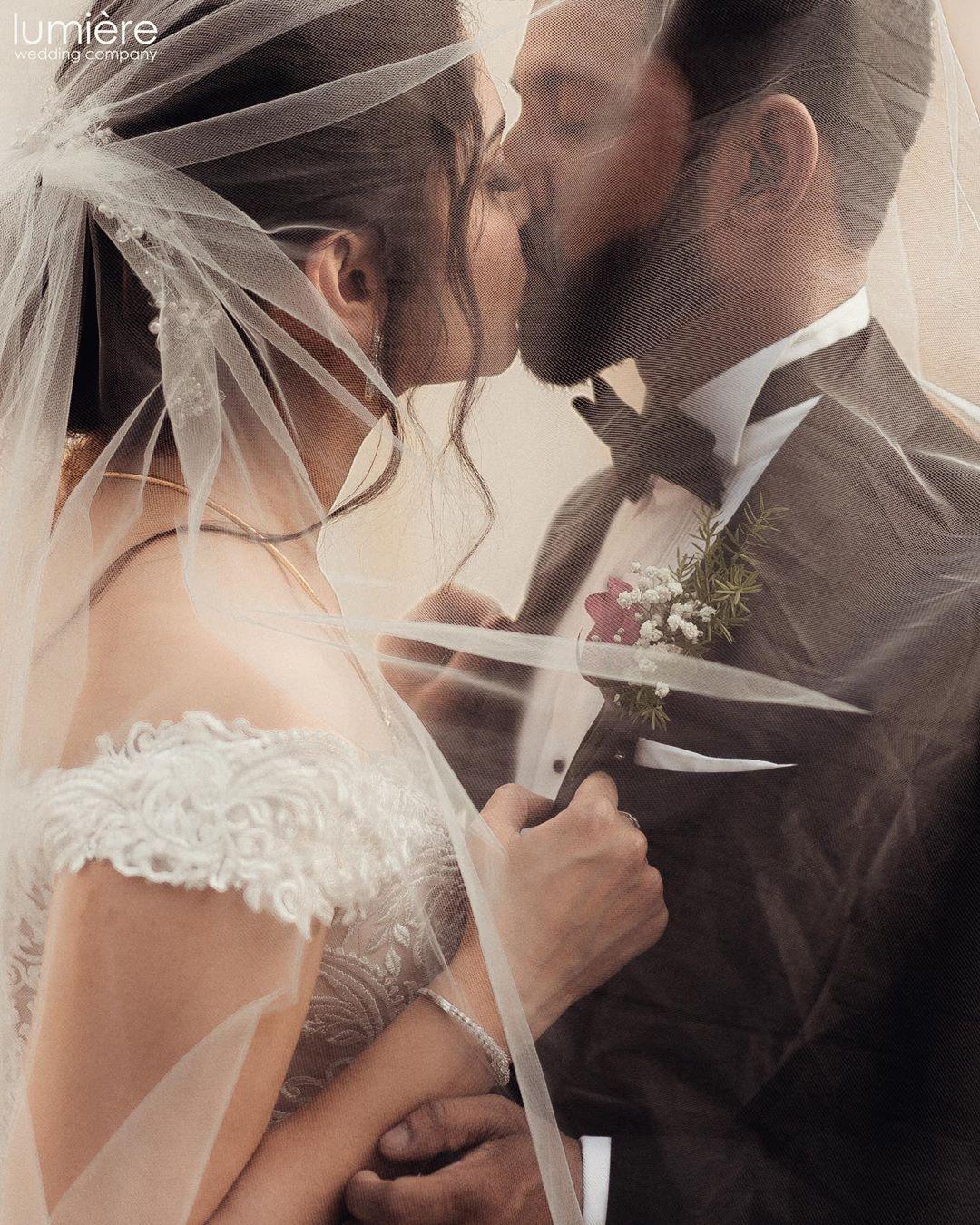 Young Indian Bride groom posing for photograph. Groom kissing the forehead  of bride. The couple is wearing traditional indian wedding dress which is  designer lehenga for bride and sherwani for groom. Stock-bilde |