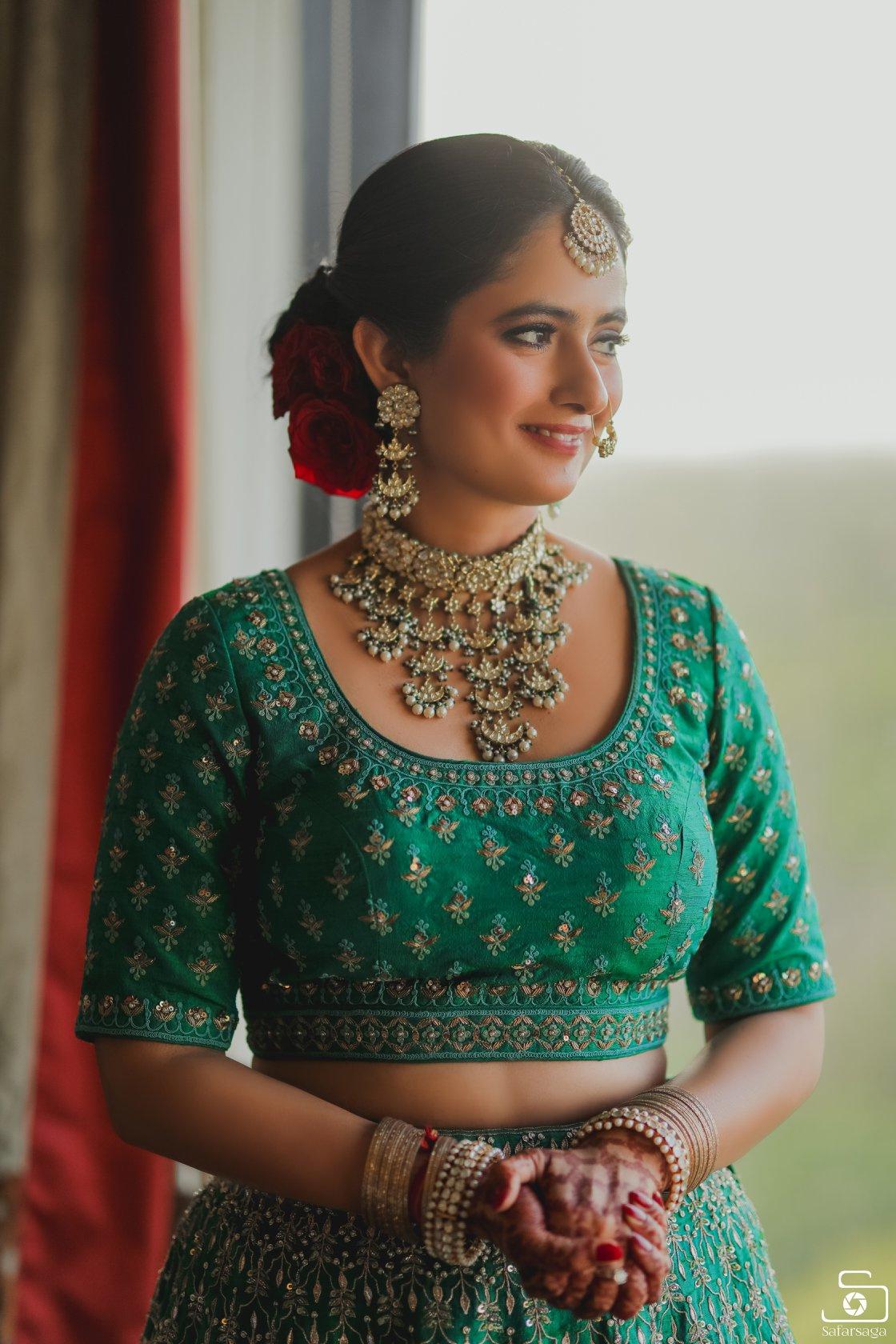 Photo of Bride wearing a pastel pink lehenga with a choker necklace.