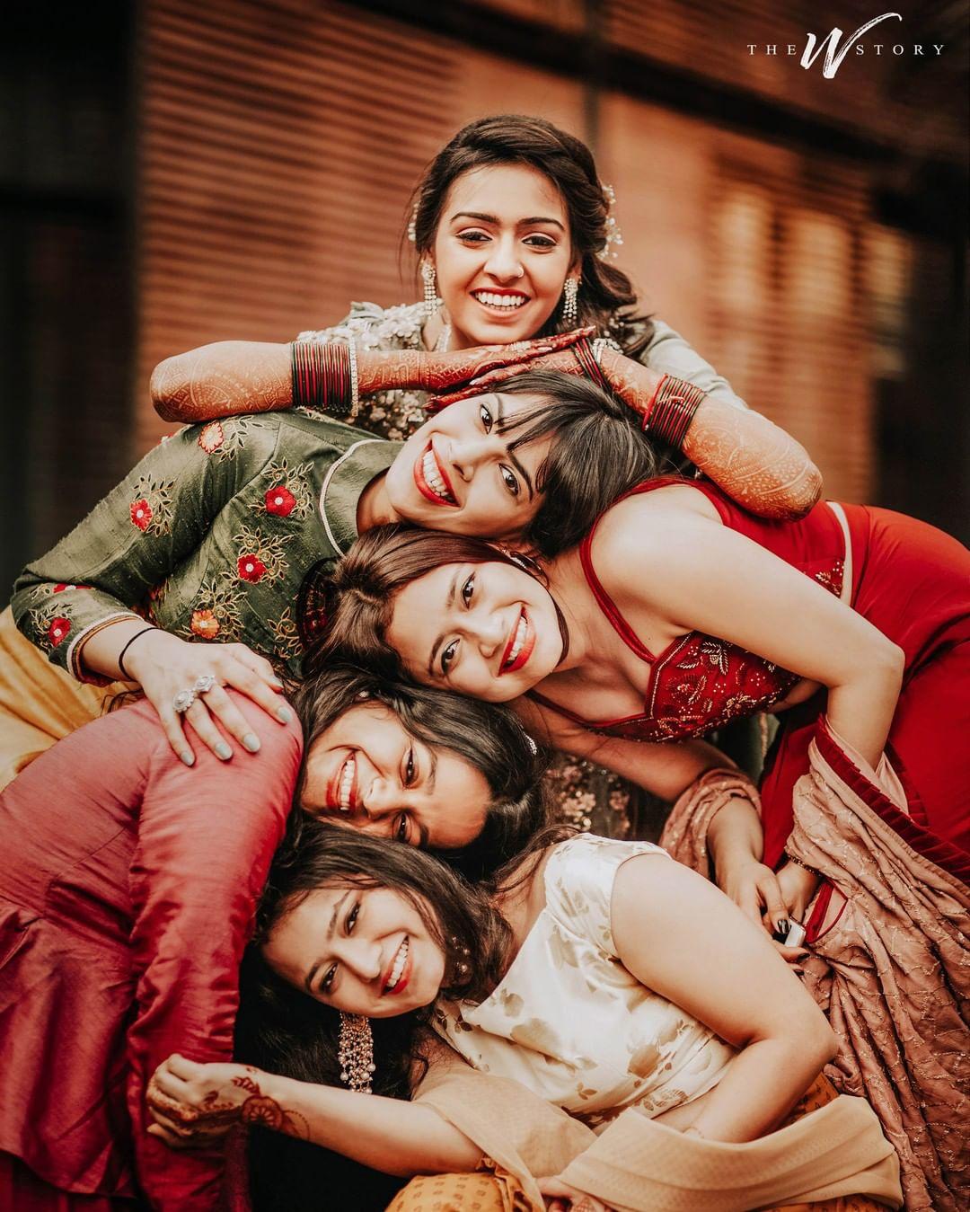 Beautiful bride sitting and posing with bridesmaids on the field full of  flowers on the wedding day Stock Photo - Alamy