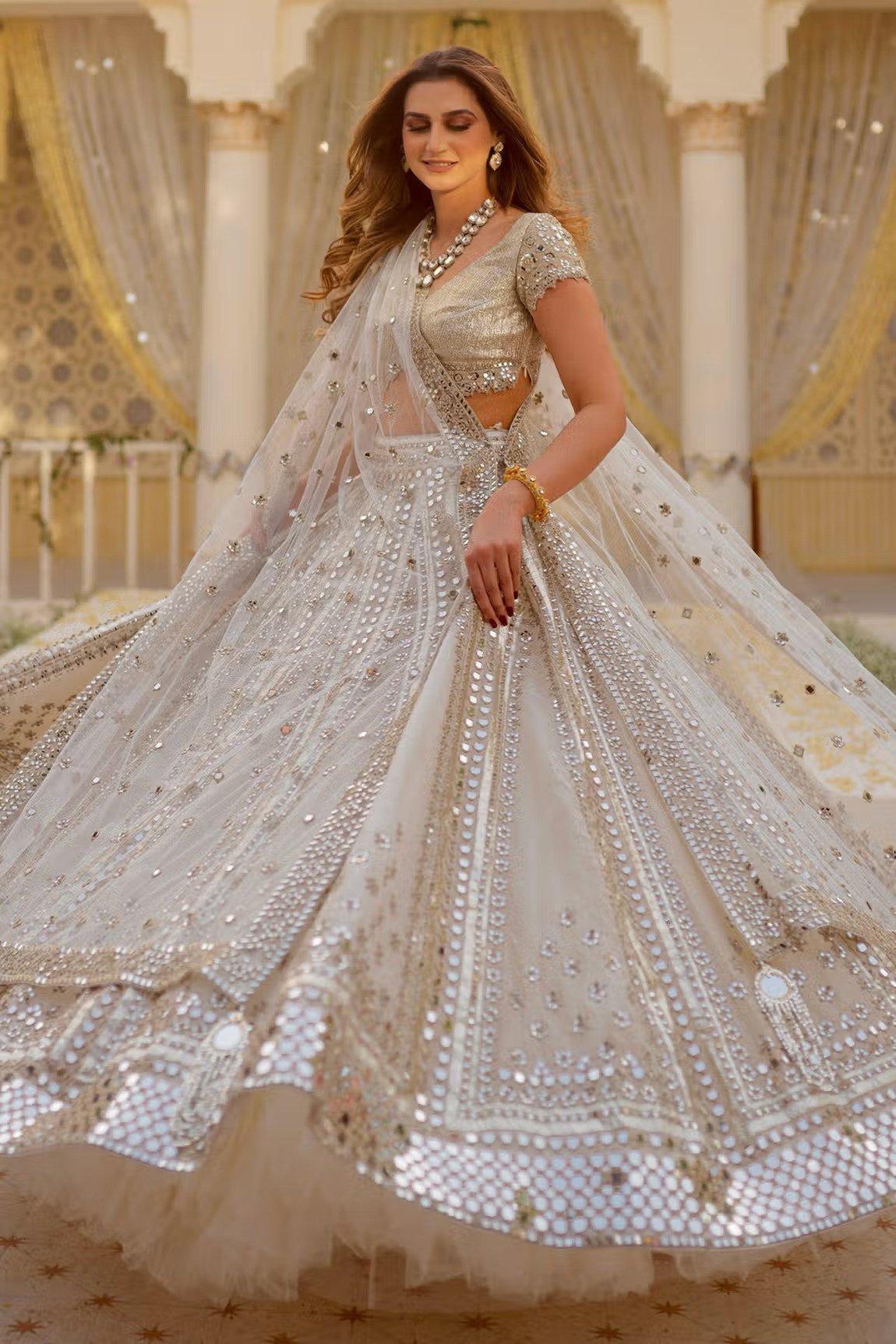 IVORY WHITE LEHENGA SET WITH AN EMBOSSED FABRIC DETAILED SKIRT AND HAND  EMBROIDERED BLOUSE PAIRED WITH A MATCHING DUPATTA AND RUFFLED DETAIL. -  Seasons India