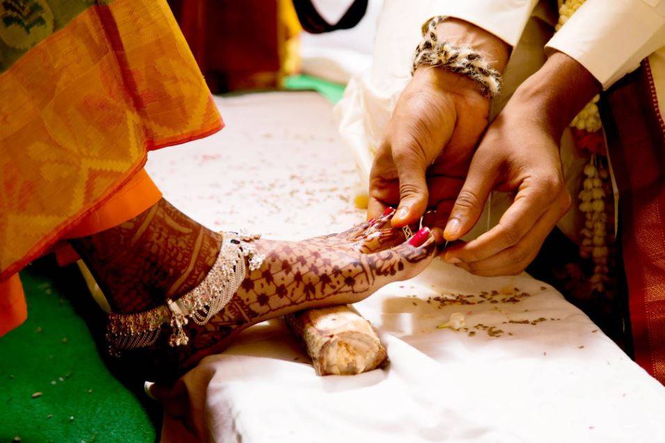 Inserting the ring in toe finger of Bride